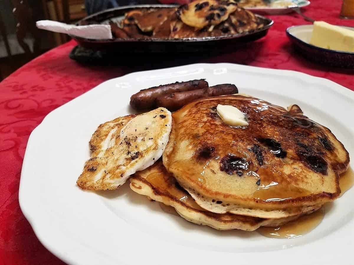 Serve Sourdough Pancakes with Syrup and Butter, Sausage Links and Fried Eggs