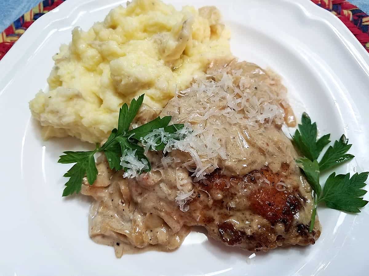 Serving Creamy Garlic Chicken with Mashed Potatoes. Garnished with fresh parsley.